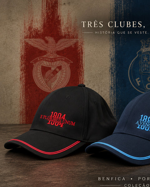 Two baseball caps for Benfica are displayed on a wooden surface against a textured background featuring the club's red and blue colors. The cap in the foreground is black with red embroidery and a red piping accent on the brim, while the cap behind it is navy blue with light blue embroidery and a light blue piping accent.