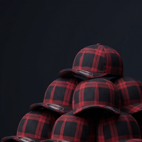 A stack of red and black plaid snapback caps arranged in a pyramid against a dark studio background.