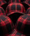 A close-up arrangement of red and black buffalo plaid baseball caps, showing the fabric texture and pattern details.