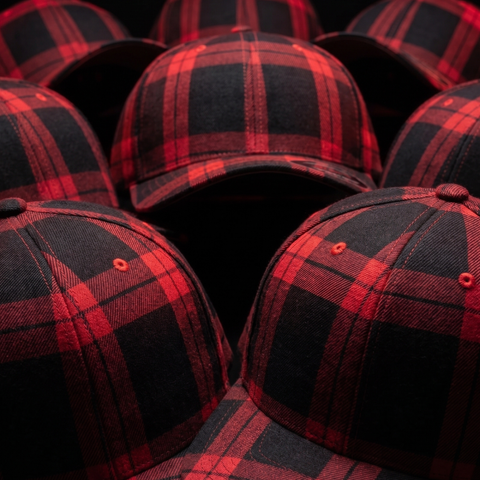 A close-up arrangement of red and black buffalo plaid baseball caps, showing the fabric texture and pattern details.