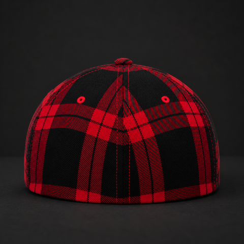 A structured baseball cap featuring a bold red and black buffalo plaid pattern, photographed against a dark, seamless studio background.