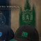 Three Sporting Portugal baseball caps displayed on a dark wooden surface against a textured backdrop. The center cap is black with a green embroidered '1906 GLORIA' logo and a green piping accent along the brim.