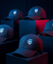 Five black baseball caps displayed on dark geometric pedestals, each featuring an embroidered skull with a blue cap and red 'FINGER' text on the front.