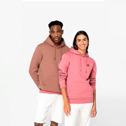 A man and a woman modeling matching pink and dusty rose hoodies against a clean white studio background.