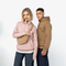 A man and a woman modeling Fjälä hoodies and a matching tan crossbody bag against a clean white studio background. The woman wears a dusty pink hoodie, and the man wears a camel brown hoodie.