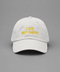 A white cotton baseball cap with yellow embroidered text reading 'LATE BUT GREAT' on the front, photographed against a solid gray background.