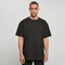 A man wearing an oversized black t-shirt with a small red embroidered skull graphic on the left chest, photographed against a neutral light gray background.